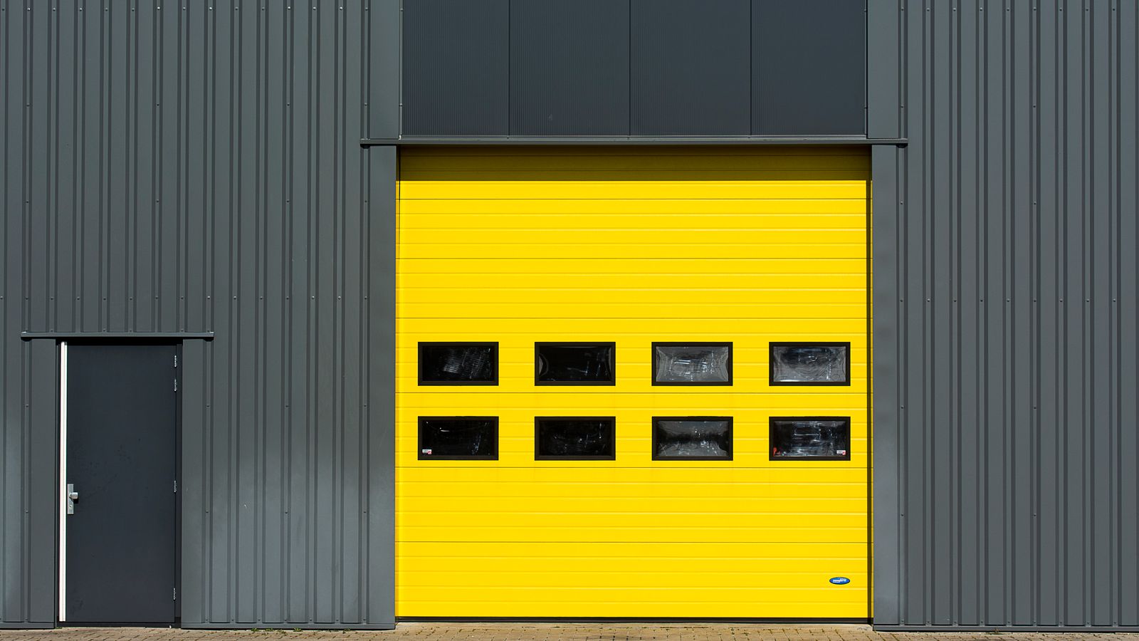 Modern home exterior at dusk with a sleek dark navy sectional garage door